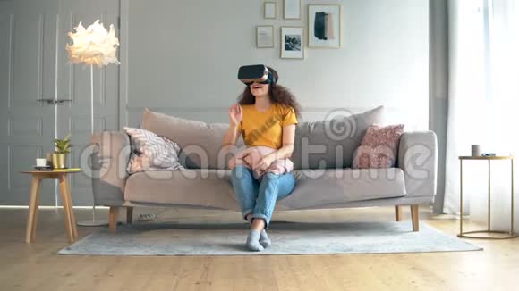 一个女孩用VR眼镜坐在沙发上机器人半机器人和人类概念视频的预览图