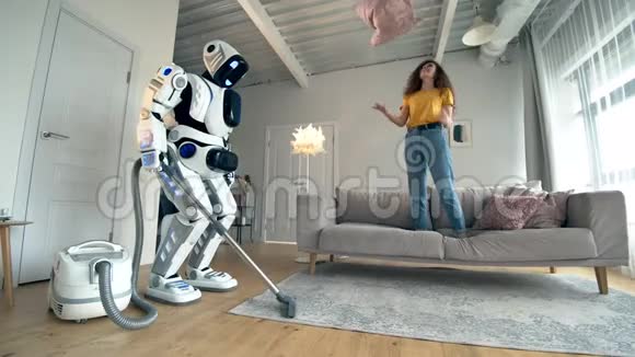 一位女士正在玩枕头而一个机器人正在打扫卫生视频的预览图