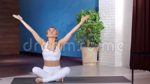 健身瑜伽女人坐在莲花的位置练习呼吸举起双手全弹视频的预览图