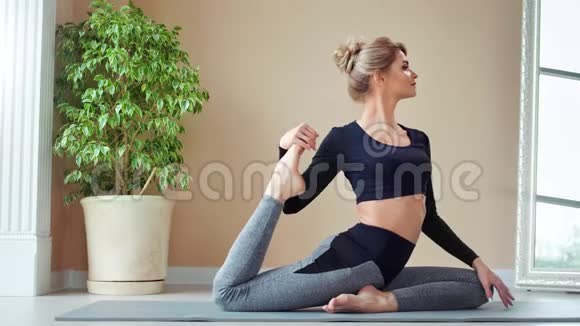 愉快的微笑欧洲健身年轻女子在现代瑜伽工作室的垫子上做伸展运动视频的预览图