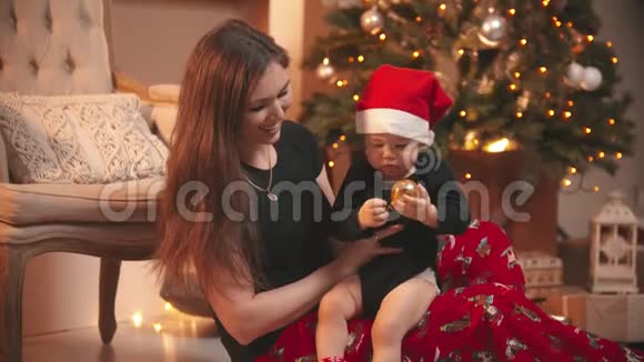 圣诞节概念一个微笑的女人和她的小儿子玩婴儿拿着金色的圣诞球视频的预览图
