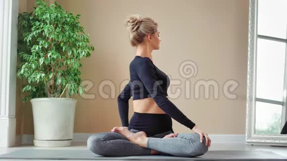 积极的瑜伽女人坐在莲花姿势显示完美的伸展享受普拉提健身课视频的预览图