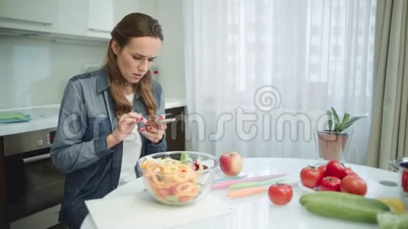 女人在现代厨房里用手机家庭主妇在找食谱视频的预览图