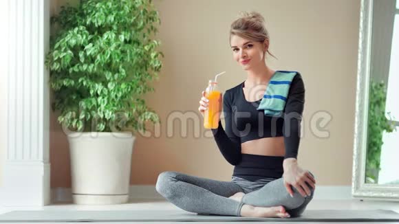 积极运动的女性喜欢喝新鲜的维生素橙汁坐在交叉的腿上视频的预览图