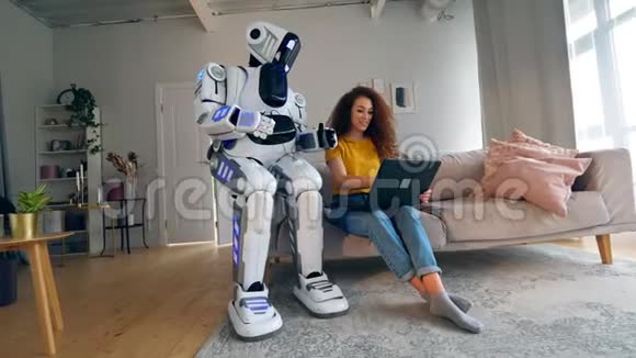 机器人半机器人和人类概念一个女孩和一个机器人在房间里用笔记本电脑工作视频的预览图