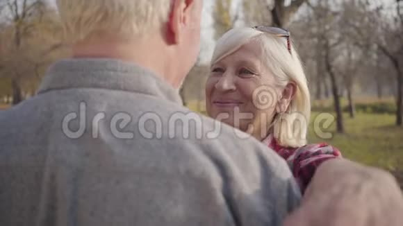 一个快乐的高白种人女人拥抱她可爱的丈夫的肖像成熟的退休夫妇度过阳光明媚的夜晚视频的预览图