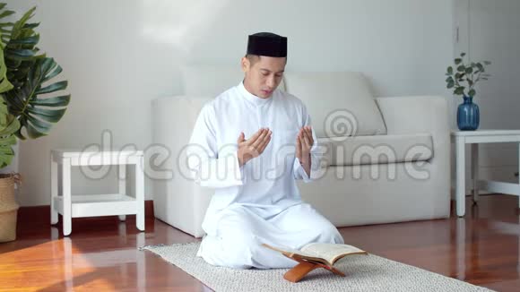 年轻的穆斯林穿着伊斯兰服装读着古兰经祈祷视频的预览图