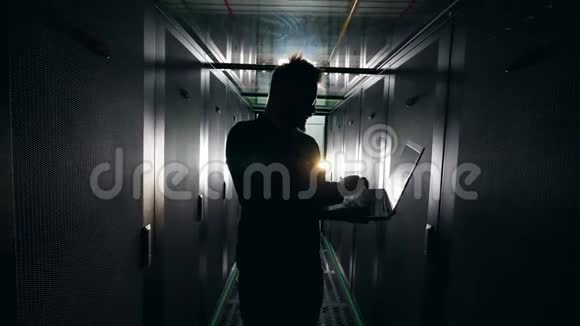 黑暗的服务器机房一名男性技术人员操作笔记本电脑IT网络安全概念视频的预览图