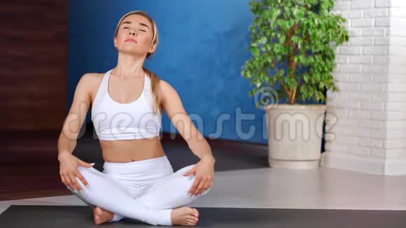 灵活的年轻女孩放松身体坐在莲花位置现代瑜伽工作室视频的预览图