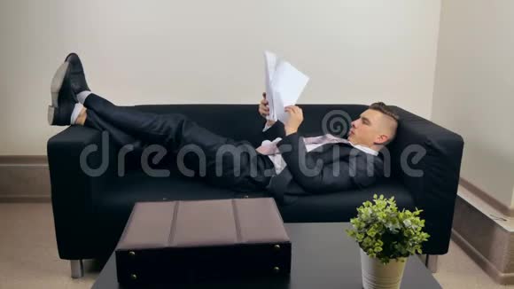 商人躺在沙发上看文件视频的预览图