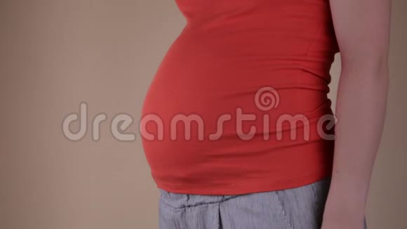 一个穿蓝色T恤的孕妇腹部的特写镜头它用手展示成功手握一块视频的预览图