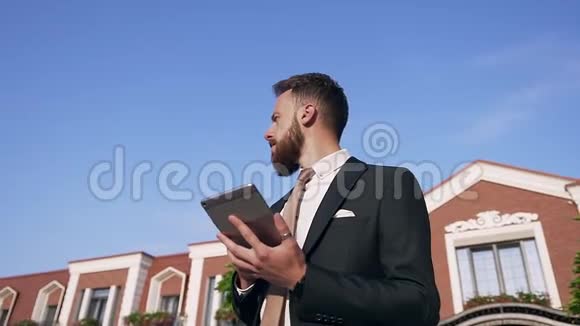 一幅严肃的商人画像手里拿着精心打扮的胡子和石碑站在漂亮的房子附近视频的预览图