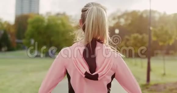 带耳机慢跑妇女的后景视频的预览图