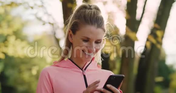 运动的女人在慢跑前用智能手机视频的预览图