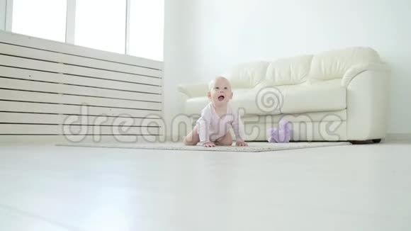 可爱的女婴在阳光明媚的白色房间里学习爬行视频的预览图