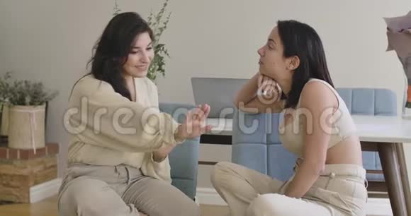 两个年轻的高加索女孩坐在软椅子上聊天一位留着黑发的漂亮女人给她修指甲视频的预览图
