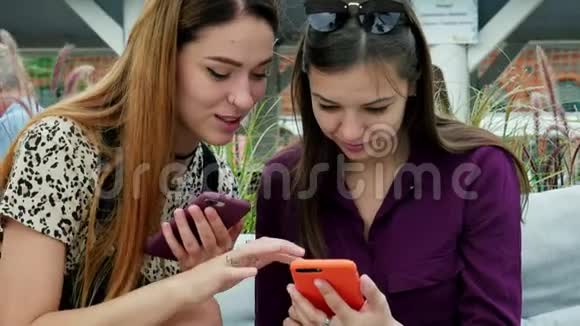 两个有魅力的年轻女人用手机聊天在露台享受美好时光的朋友们视频的预览图