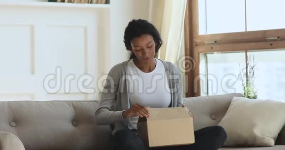 令人惊讶的年轻非洲女人在家打开包裹视频的预览图