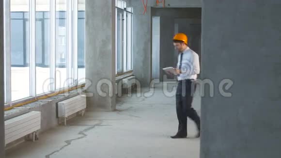 建筑工程师商人房地产经纪人在一座新建筑内使用平板电脑检查施工现场视频的预览图