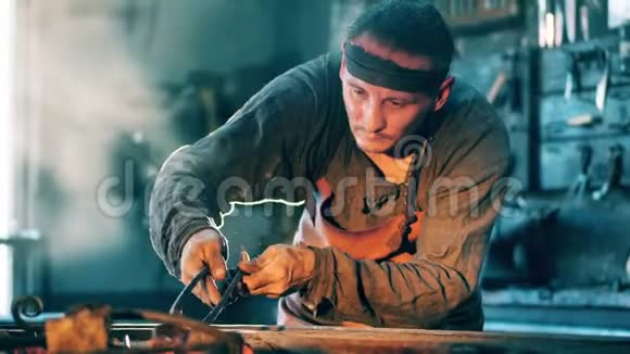 一个人拿着金属钳在锻炉上用刀工作视频的预览图