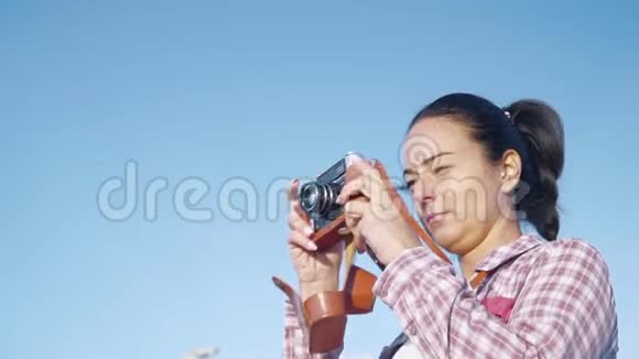 拥有复古相机的美丽女人在早晨的天空中拍照视频的预览图