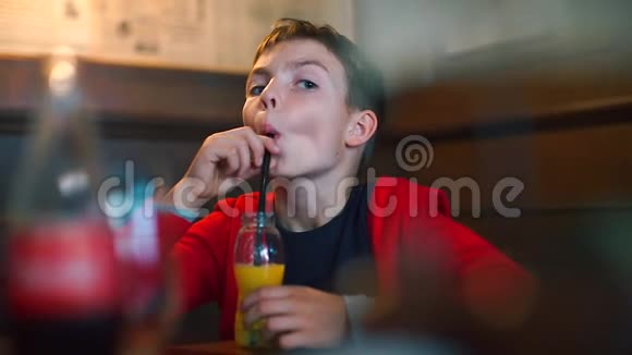 学校餐厅里的男孩用吸管喝瓶子里的果汁视频的预览图