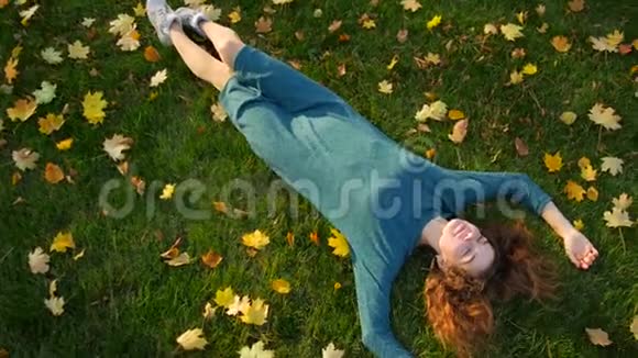 穿着裙子的女孩躺在绿草上上面有黄叶视频的预览图