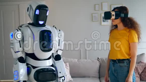 一个穿着VR眼镜的女孩正在和一个机器人接触视频的预览图