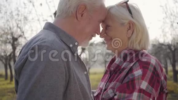 微笑的老白种人家庭的肖像站在阳光下靠着头快乐成熟的欧洲夫妇视频的预览图