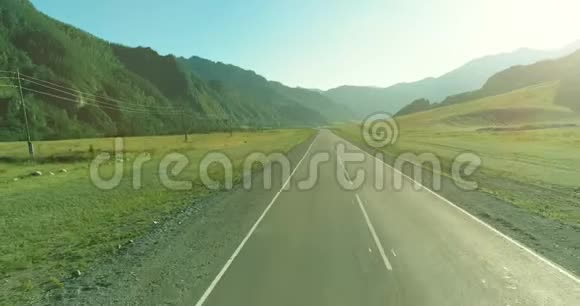 在阳光明媚的夏季早晨低空飞越山路和草地视频的预览图