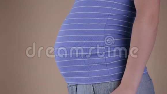 一个穿着蓝色T恤的孕妇腹部的特写镜头她手中拿着传单视频的预览图