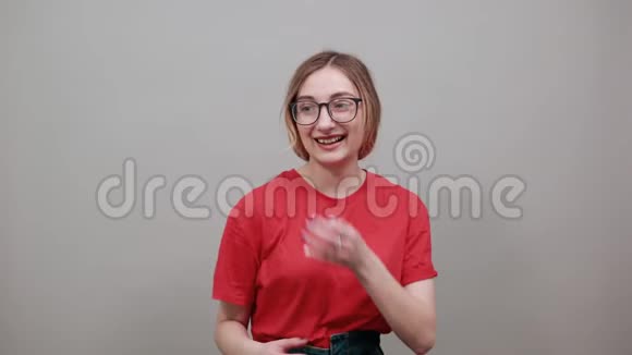 穿红色衬衫的开朗女人戴着漂亮的眼镜指着旁边微笑着视频的预览图