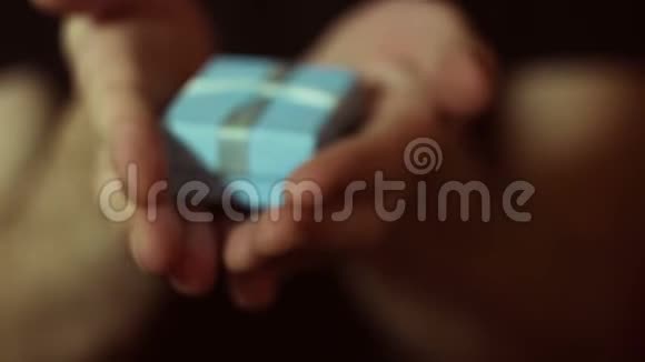 男人在一个蓝色的盒子里拿出一份礼物一个年轻人的手在一个蓝色小盒子里捧着新年礼物假期的礼物视频的预览图