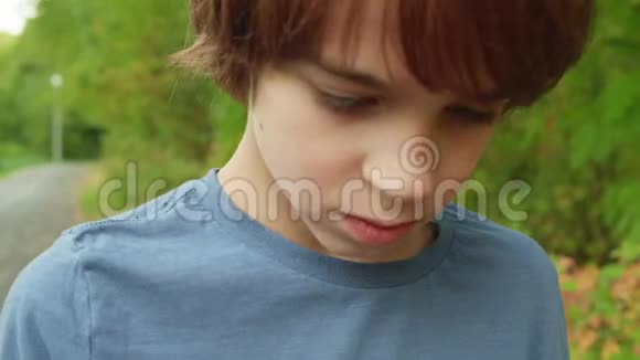 闭上脸和眼睛的少年男孩在绿色的夏树背景上肖像男孩少年看户外的东西视频的预览图