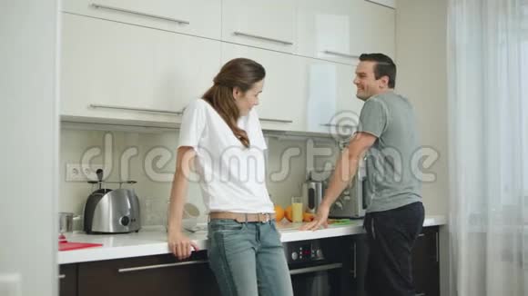 快乐的一对在厨房拥抱对方幸福的丈夫扭曲微笑的妻子视频的预览图