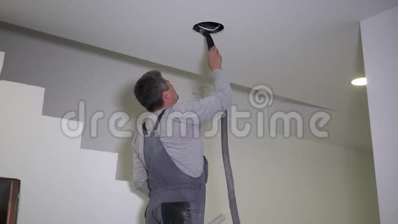 工人在天花板锯孔后用吸尘器软管吸石膏粉视频的预览图