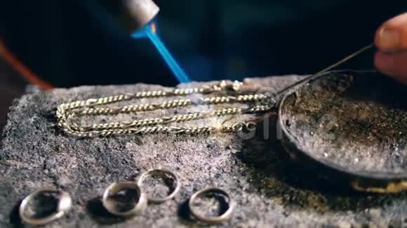 珠宝商金匠在一个专业的珠宝车间焊接一个金属链在珠宝店视频的预览图