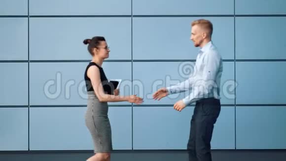 两个商务人士男人和女人互相打招呼用平板电脑在户外握手视频的预览图
