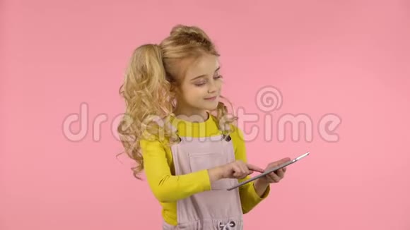 漂亮的小女孩子正在玩平板电脑并发送一个打击吻视频的预览图