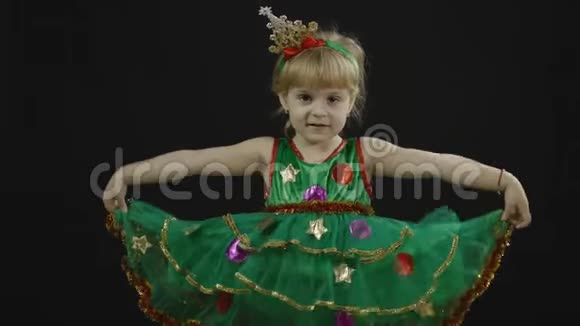 穿着圣诞树装的快乐美丽的小女孩做鬼脸跳舞视频的预览图