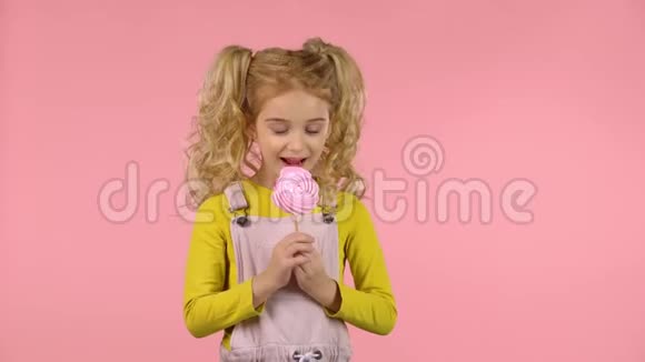 漂亮的女孩子正在吃棍子上的糖果视频的预览图