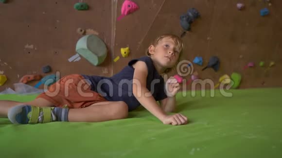 一个小男孩躺在一个巨石攀岩场的垫子上视频的预览图