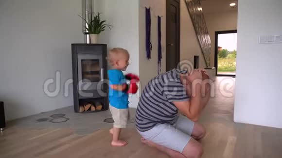 小男孩戴着拳击手套和他爸爸玩万向节运动视频的预览图