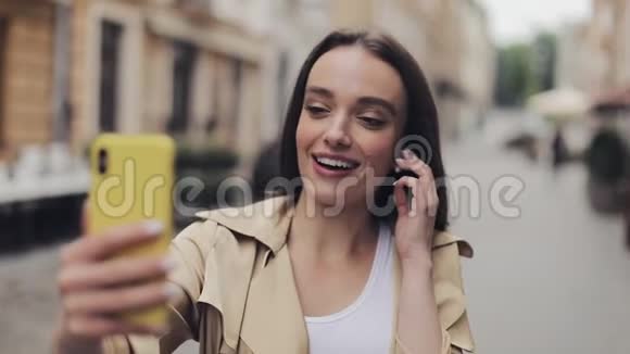 一个戴着耳机的漂亮微笑的女孩用视频通话保持电话垂直通话视频的预览图