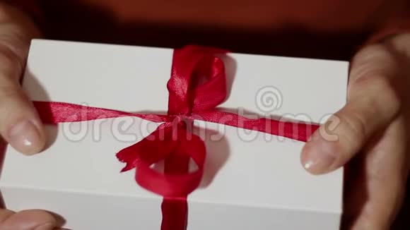美丽的女孩打开她的礼物美丽的双手打开一个女孩新年礼物解开一条红丝带假期的礼物礼品视频的预览图