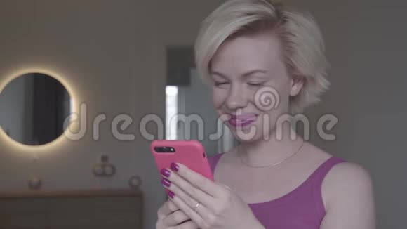 年轻女性使用智能手机在家聊天微笑慢动作视频的预览图