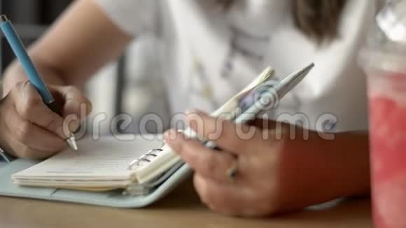 亚洲女人坐着写日记用一杯冰沙果汁激励饮料店的生活视频的预览图
