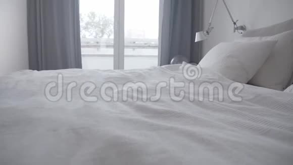 快乐的女人在家里的床上蹦蹦跳跳的慢动作侧写视频的预览图