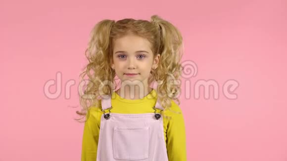 可爱的卷曲小女孩子体贴然后在粉红色背景的工作室微笑视频的预览图