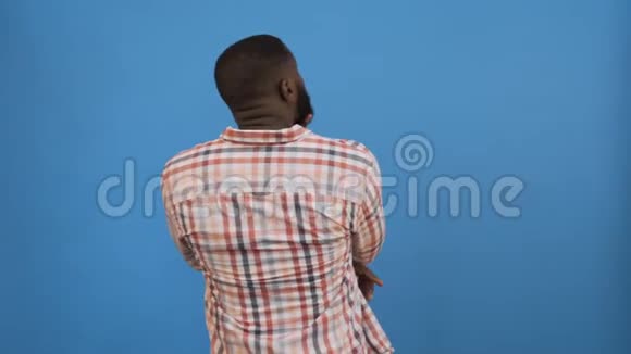 年轻的非裔美国男人穿着休闲的t恤站在孤立的黄色背景上向后倾斜4K视频的预览图